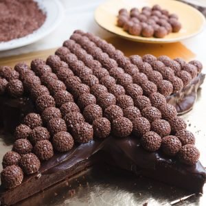 Bolo estrela grande com cobertura de brigadeiro tradicional e minibrigadeiros do mesmo sabor no topo